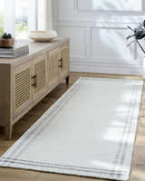 Entryway with a Nimue Cream & Charcoal Bordered Area Rug, light wood console table, and neutral decor. Roomscene-Runner
