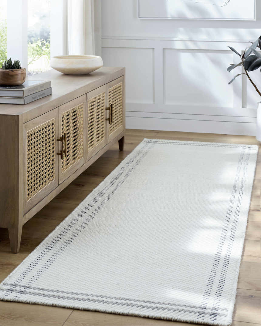 Entryway with a Nimue Cream & Charcoal Bordered Area Rug, light wood console table, and neutral decor. Roomscene-Runner