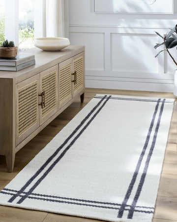 Entryway scene with a light wood console and the off-white Nimue Bordered Wool Rug runner on a wood floor. Roomscene-Runner