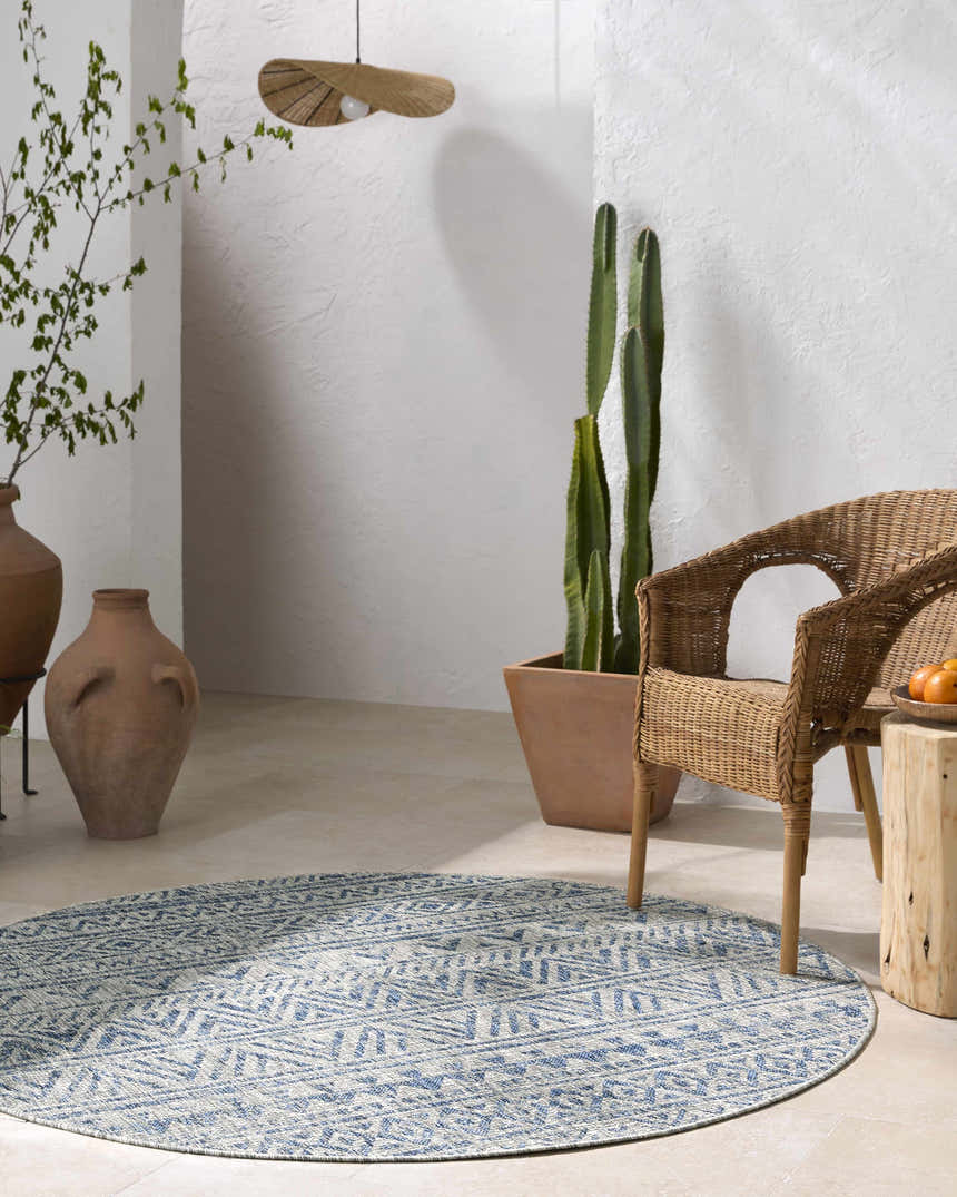 Coastal patio with a round Novato All Over Pattern Performance Rug, wicker chair, and potted cactus. Roomscene-Round