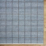 Close-up of the slate blue Ayinde Area Rug. Hand woven, recycled PET yarn rug with a contemporary grid pattern. Corner