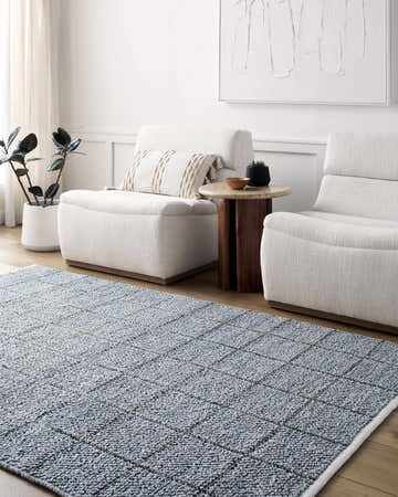 Living room scene with slate blue Ayinde Area Rug, white chairs, wood side table, and modern art. Roomscene-Rectangle