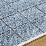 Close-up of the Ayinde Area Rug showing slate blue recycled PET yarn and a hand-woven contemporary grid pattern. Texture