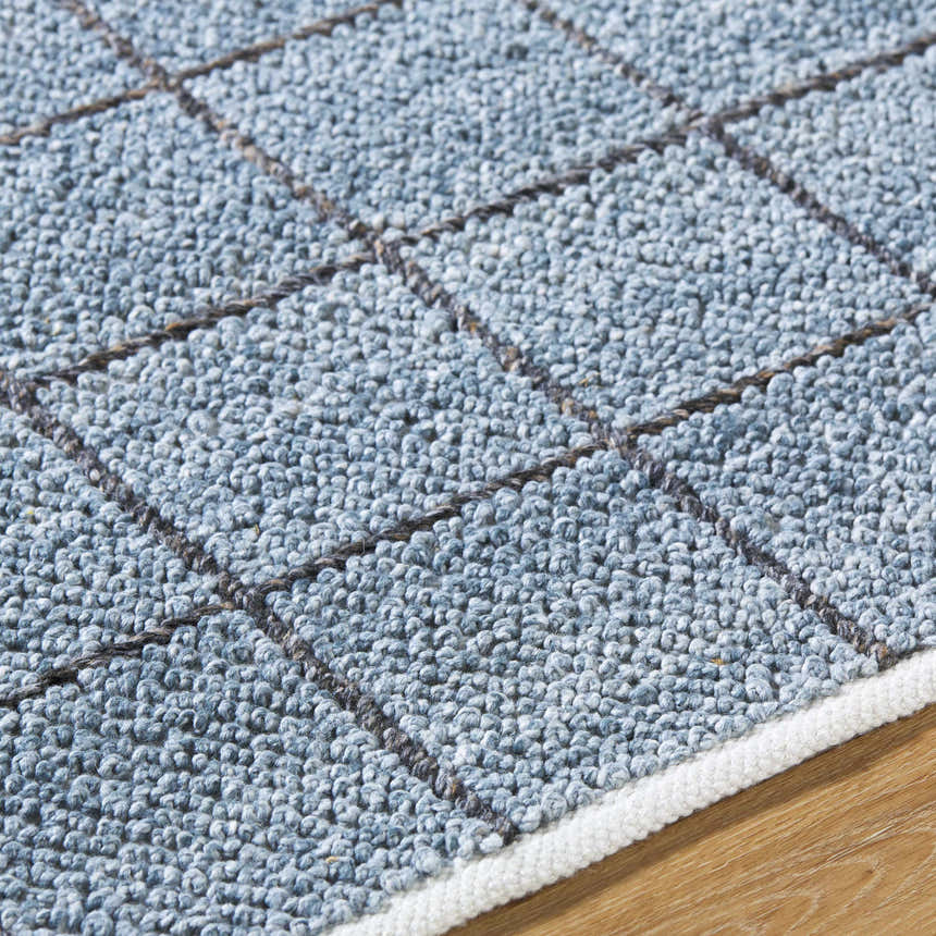 Close-up of the Ayinde Area Rug showing slate blue recycled PET yarn and a hand-woven contemporary grid pattern. Texture