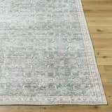 Close-up of Ayanna Washable Area Rug. Traditional design in cream, teal, tan, and dark red on wood floor. Front