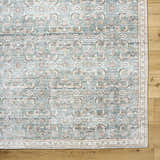 Close-up of Ayanna Washable Area Rug featuring a traditional pattern in cream, dark red, pale blue, tan, and teal. Corner