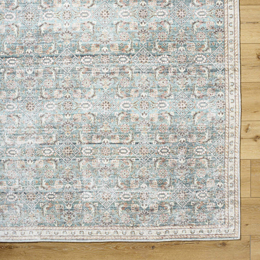 Close-up of Ayanna Washable Area Rug featuring a traditional pattern in cream, dark red, pale blue, tan, and teal. Corner