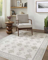 Living room scene with a beige chair on an Aquene Ivory Washable Area Rug with blush, sage, and sky blue floral pattern. Roomscene-Rectangle
