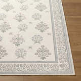 Close-up of Aquene Ivory Washable Area Rug showing floral pattern in blush, sage, sky blue, and taupe on a textured ivory background. Front