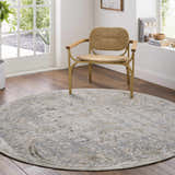 Sunlit room scene with a round Nasir Thick Luxe Boutique Rug in charcoal, cream, and gray under a woven chair. Roomscene-Round