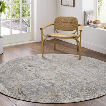 Sunlit room scene with a round Nasir Thick Luxe Boutique Rug in charcoal, cream, and gray under a woven chair. Roomscene-Round