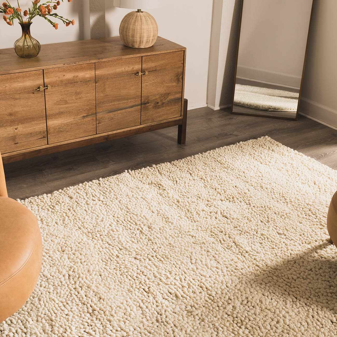 Entryway scene with a cream Oakridge Area Rug, wood cabinet, mirror, and tan leather ottoman. Roomscene-Rectangle
