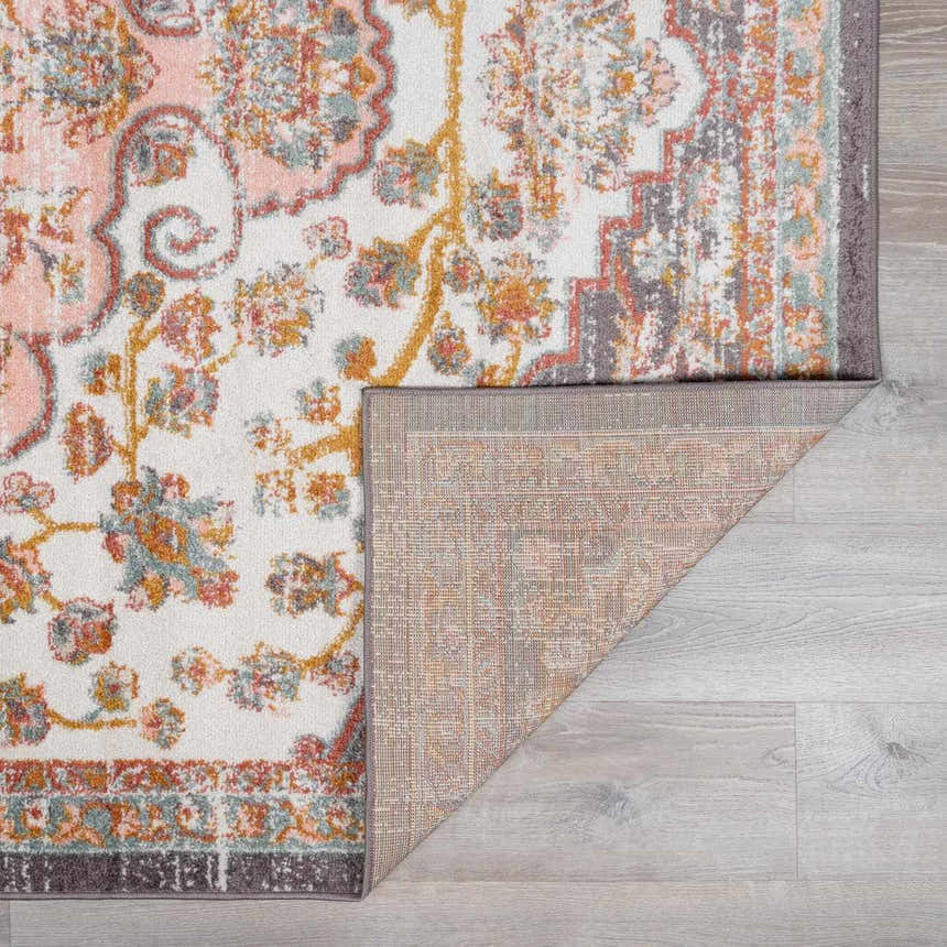Close-up of the Oark Floral Medallion Area Rug. Features a floral pattern in brick red, camel, and dusty pink on an off-white base. Fold