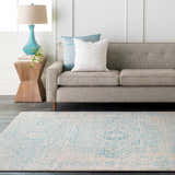 Living room scene with light beige Omega Area Rug, gray sofa, teal lamp, and wood side table. Roomscene-Rectangle
