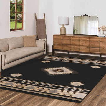 Living room with a black Buckhaven Southwestern Area Rug, beige sofa, and wooden cabinet. Roomscene-Rectangle