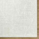 Close-up of the Pabla Cream Area Rug showing its ivory color and subtle geometric pattern. Corner