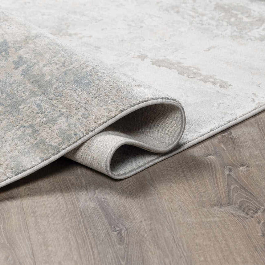 Close-up of the Pialba rug showing its abstract smokey design, luxe texture, and colors like light gray and dusty sage. Fold