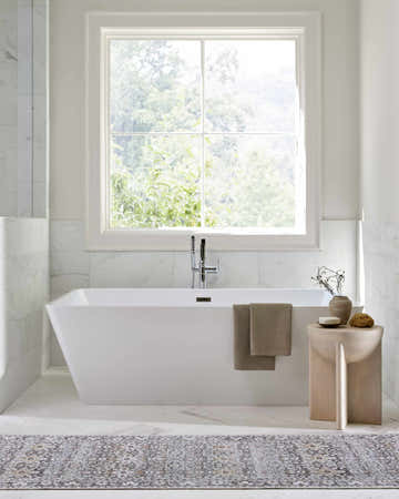 Bright bathroom scene with a white tub and Our PNW Home Rainier Damask Brown Washable Rug on the marble floor. Roomscene-Rectangle