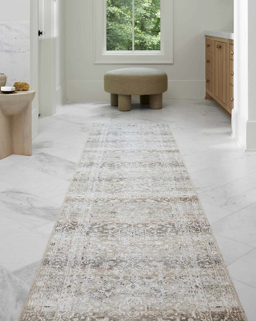 Light brown Rainier Damask Washable Rug runner in a bright bathroom with marble floors, tan stool, and wood vanity. Roomscene-Runner