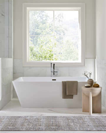 Bright bathroom scene with a white tub and Rainier Damask Dark Brown Washable Rug on marble tile floor. Roomscene-Rectangle