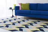 Living room scene with a blue sofa and Pojoaque Area Carpet in dark blue, pink, and olive geometric pattern. Roomscene-Rectangle