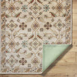 Close-up of the hand-tufted Postelle Wool Rug with a traditional floral pattern in brown, sage, and tan on a light background. Fold