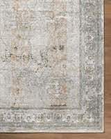 Close-up of the Pryce Sage rug showing a traditional design in cream, light brown, and light gray on a wood floor. Corner