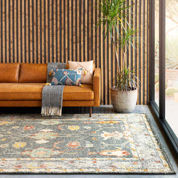 Living room scene with a leather sofa and the Prosperidad Handmade Wool Rug in brick red, charcoal, cream, and light beige. Roomscene-Rectangle