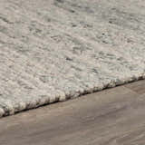 Close-up of the hand woven Olisa Gray Wool Area Rug showing its light gray and natural gray tones and textured wool loops. Pile
