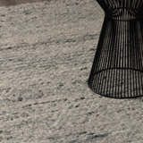 Close-up of Olisa Gray Wool Area Rug showing its light gray and natural gray tones and textured, hand-woven construction. Styleshot
