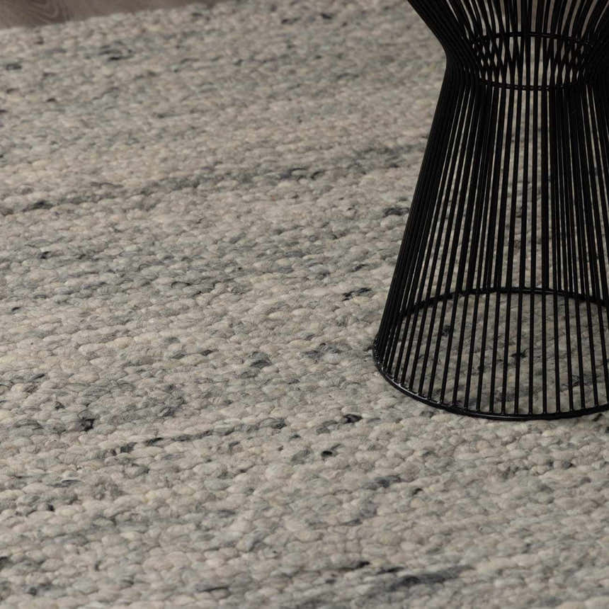 Close-up of Olisa Gray Wool Area Rug showing its light gray and natural gray tones and textured, hand-woven construction. Styleshot
