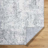 Close-up of the Avital Area Rug. Contemporary style in gray, charcoal, black, and white. Machine woven texture. Fold