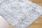 Close-up of the Annlea Washable Area Rug. Farmhouse style rug with blue, sage, and white traditional pattern detail. Corner