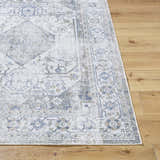 Close-up of the Annlea Washable Area Rug. Traditional rug design in blue, sage, and white on a wood floor. Front
