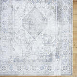 Close-up of the Annlea Washable Area Rug. Farmhouse style rug in blue, sage, and white with a traditional, machine-woven pattern. Corner