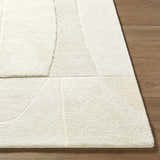 Close-up of the hand-tufted Agneza Area Rug, a contemporary wool rug in beige, cream, and ivory, on hardwood floor. Front