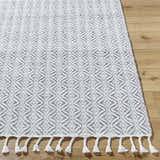 Close-up of the Anelia Medium Gray Area Rug showing its diamond pattern, hand-woven texture, and fringe. Front