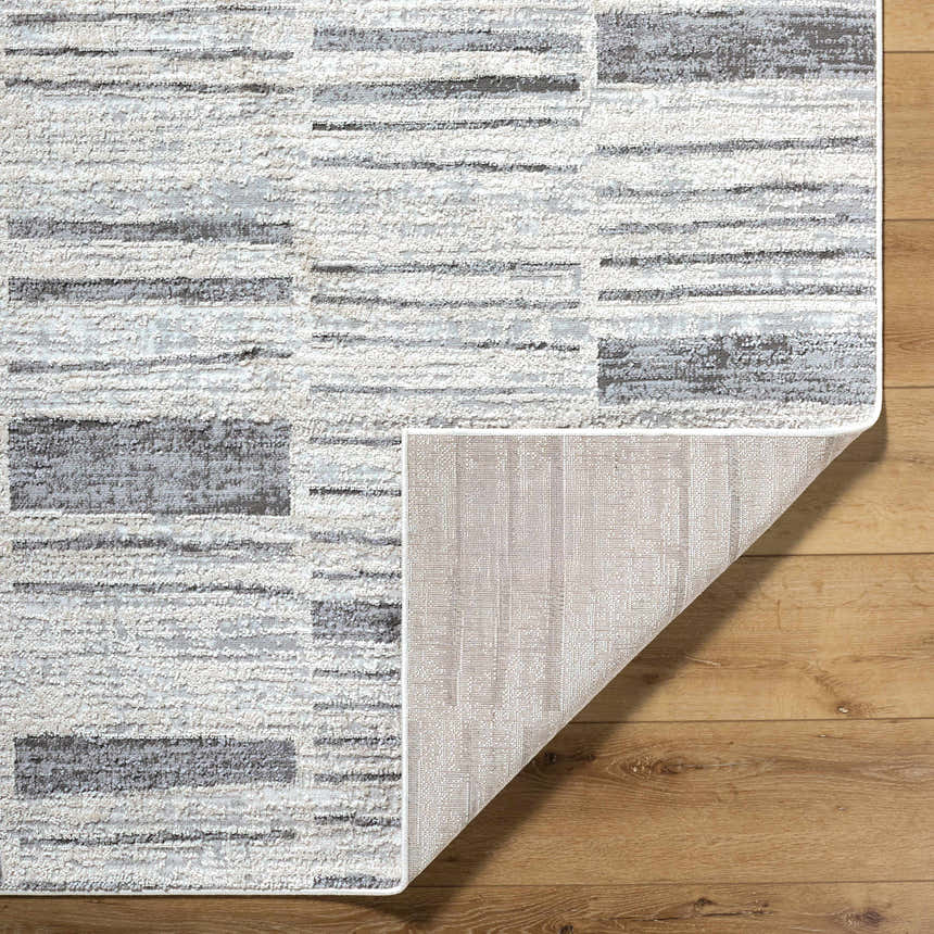 Close-up of Allete Broken-Striped Area Rug showing ash, light silver, and gray tones with a textured, machine-woven design. Fold