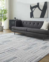 Living room scene with gray sofa and Allete Broken-Striped Area Rug in ash, light silver, and silver gray. Roomscene-Rectangle