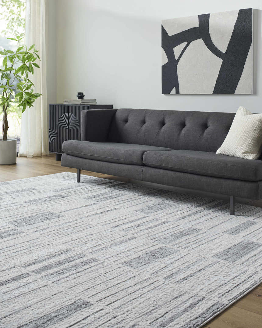 Living room scene with gray sofa and Allete Broken-Striped Area Rug in ash, light silver, and silver gray. Roomscene-Rectangle