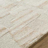 Close-up of the Aintza Area Rug, a hand-tufted wool rug in beige, cream, ivory, and tan with a subtle geometric pattern. Texture