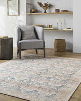 Living room scene with gray chair and Arushi Washable Area Rug in cream, green, orange, and rust tones. Roomscene-Rectangle