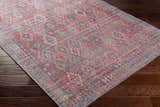 Close-up of the Ranao Washable Area Rug on dark wood floor. Traditional, vintage style with blue, red, and green colors. Corner