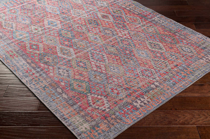 Close-up of the Ranao Washable Area Rug on dark wood floor. Traditional, vintage style with blue, red, and green colors. Corner