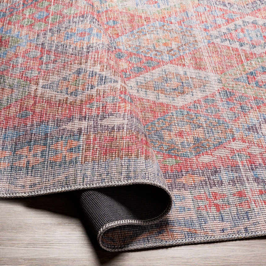 Close-up of the Ranao Washable Area Rug showing its traditional, vintage design with blue, red, peach, and green colors. Fold