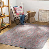 Living room scene with a Ranao Washable Area Rug in blue, red, and green, styled with a butterfly chair and wood accents. Roomscene-Rectangle