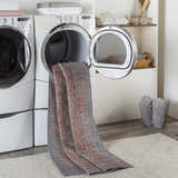 Laundry room scene with Ranao Washable Area Rug coming out of dryer. Farmhouse style with gray wood-look floors and white appliances. Washing-Machine