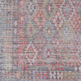 Close-up of the Ranao Washable Area Rug - Clearance, featuring a traditional diamond pattern in blue, red, green, and taupe. Swatch