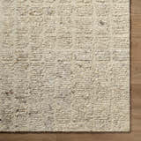 Close-up of the hand-tufted Asahel Ivory Area Rug, a farmhouse style rug made of 100% wool with a subtle geometric pattern. Corner