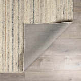 Close-up of the hand-tufted Capote Ivory Area Rug showing its wool texture and charcoal, tan, and taupe vertical stripes. Fold